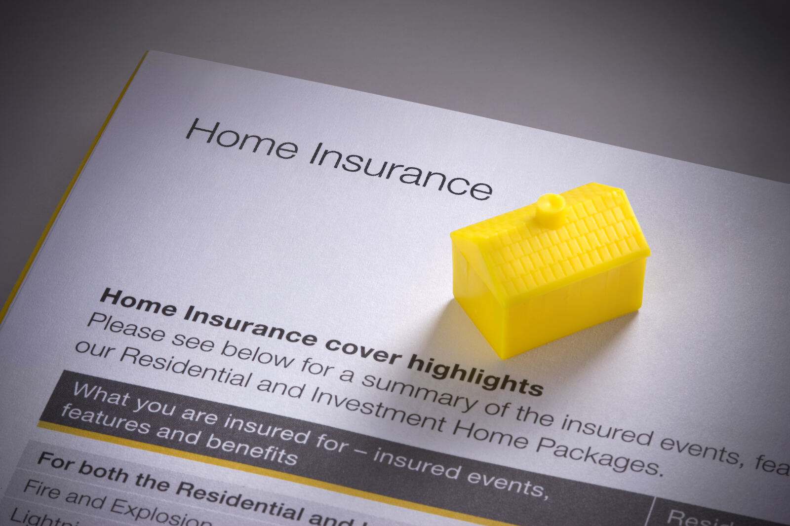 A model house held in cupped hands, representing home insurance protection