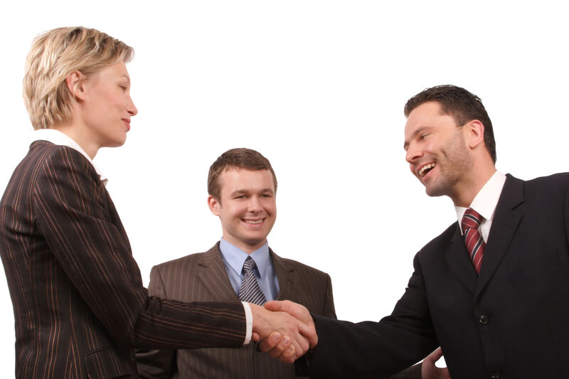 A man and a woman shaking hands across a desk after reaching an agreement